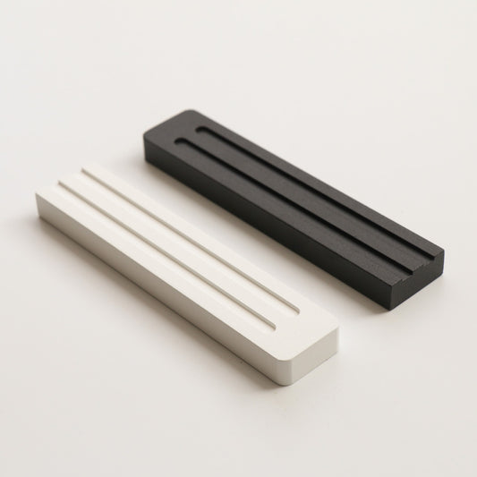 A sleek and refined mezuzah by JUDA that blends modern design with Jewish tradition. Crafted from aluminum using CNC machining and electrostatic painting, it features two clean lines that subtly form the letter Shin (ש). Available in two sizes. A meaningful and aesthetic addition to any doorway.